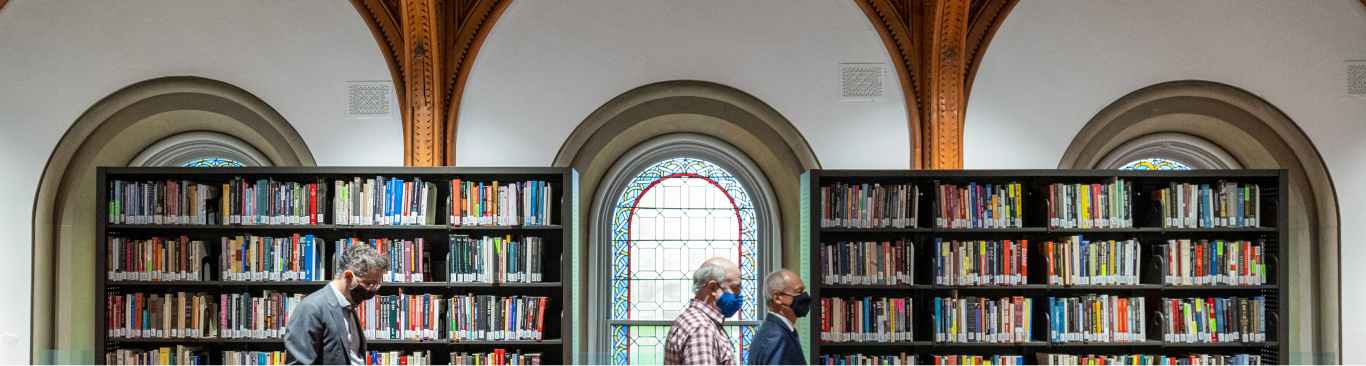 a view from inside a library. Books are in a two bookcases flanking a beautiful arched window.